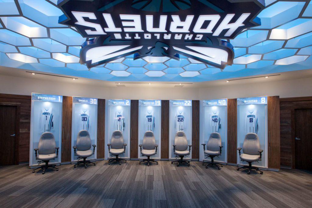 Charlotte Hornets new locker room with hybrid build custom lockers featuring frosted acrylic pocketing doors, acrylic solid surface body, and solid wood door panels with integrated technology